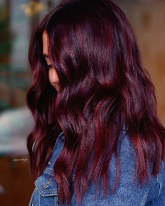 photo of a girl in a denim jacket showing off her burgundy hair 