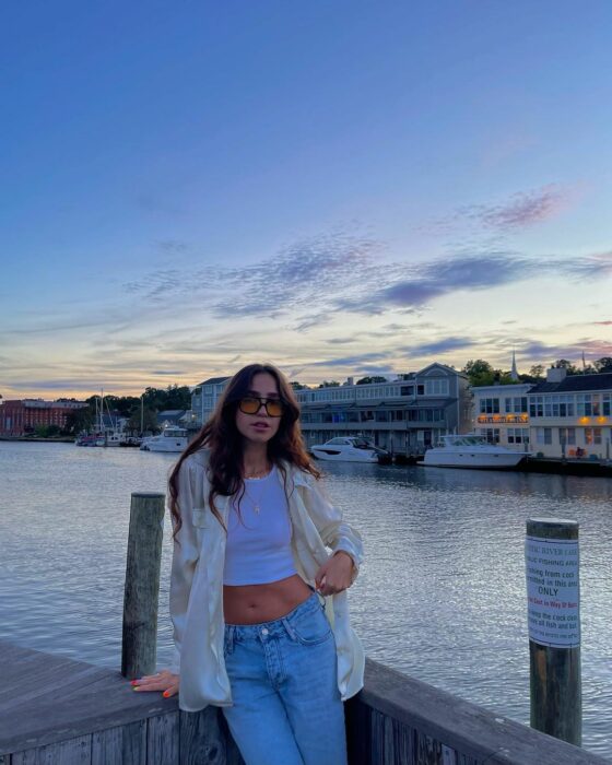 Chica posando en el muelle frente a una embarcación de barcos 