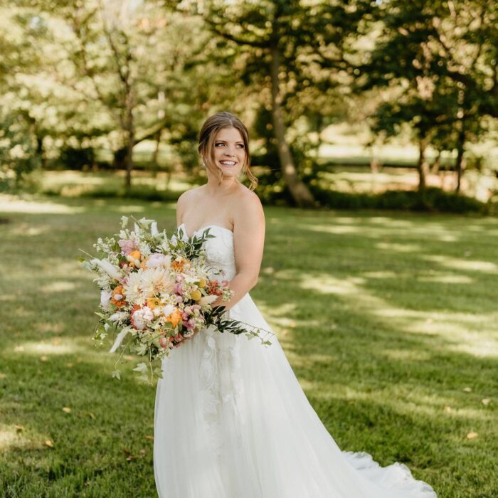 Fotografía de una chica vestida de novia posando en un jardín 