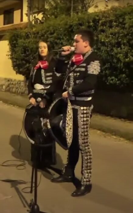 par de mariachis dando una serenata a fuera de una casa 