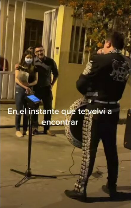 pareja de novios abrazados disfrutando de una serenata fuera de una casa 