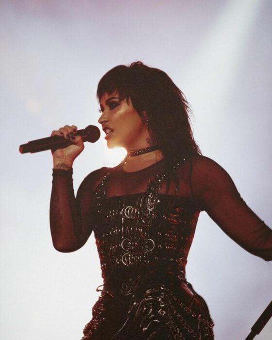 Foto de Demi Lovato con el micrófono cantando durante un concierto