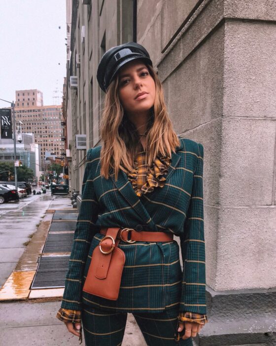 woman standing on a street with a bag hanging from her belt 