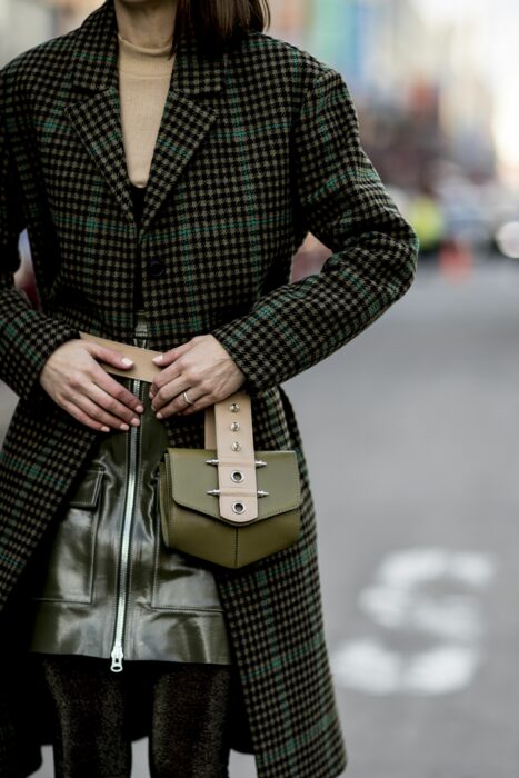 mujer posando con un outfit en color verde con un bolso colgado al cinto 