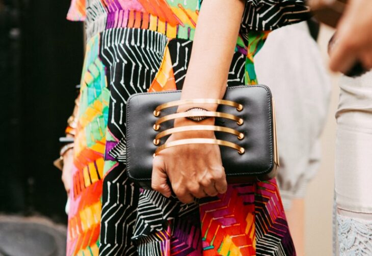 hand of a woman with a black bag hanging on the wrist with rings 