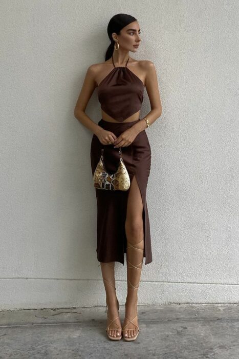 woman posing with a skirt and top set against a wall 