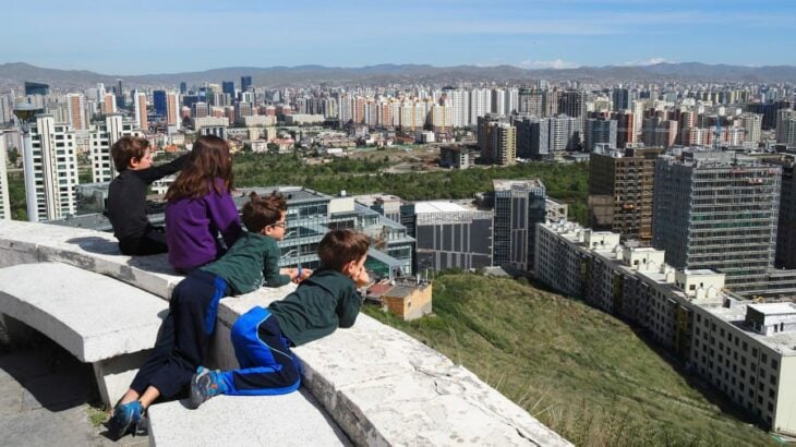 cuatro niños viendo el panorama de varios edificios en una ciudad 
