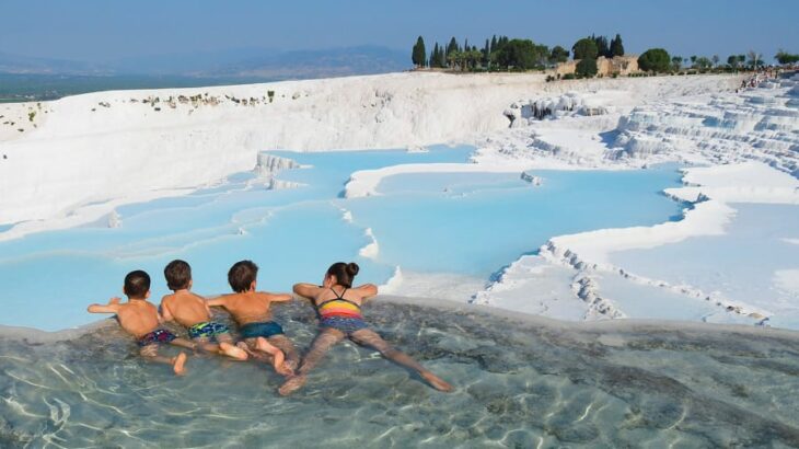 cuatro niños dentro del agua en un lugar rodeado de nieve 