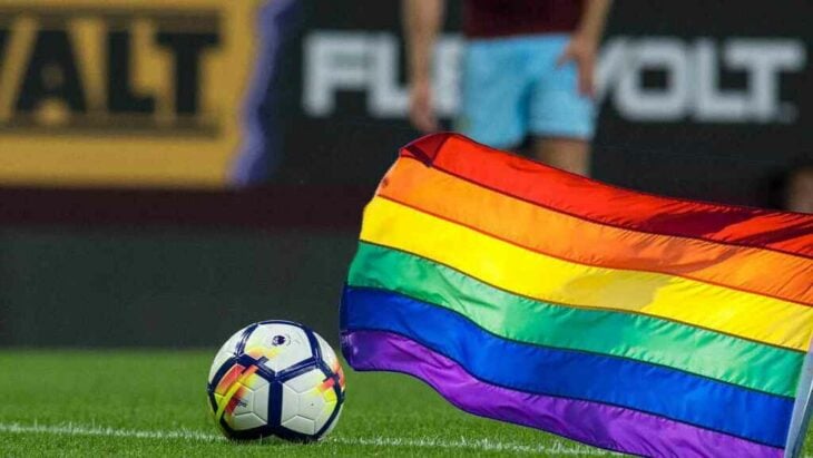 bandera del orgullo gay y un balón de fútbol en un estadio 
