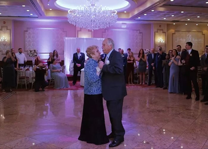 pareja de ancianos bailando en el centro de la pista de un salón de fiestas en la boda de sus nietos 