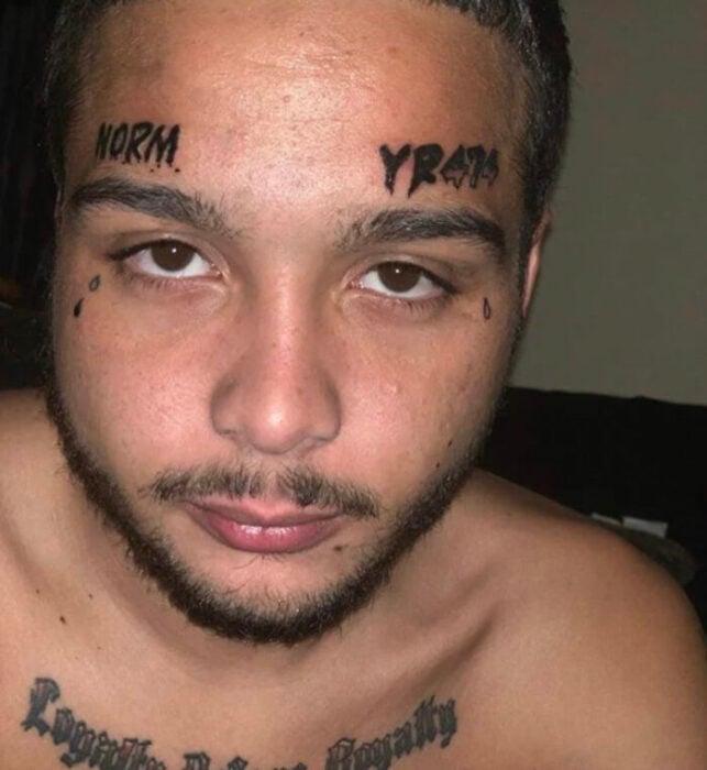 face of a guy showing a couple of tattoos above his eyebrows 