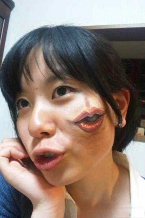 photo of a woman's face with a mouth tattoo on her cheek 