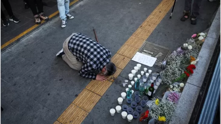 hombre orando por las víctimas de Seúl ante veladoras en la calle