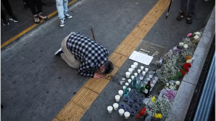 man praying for the victims of Seoul before candles in the street