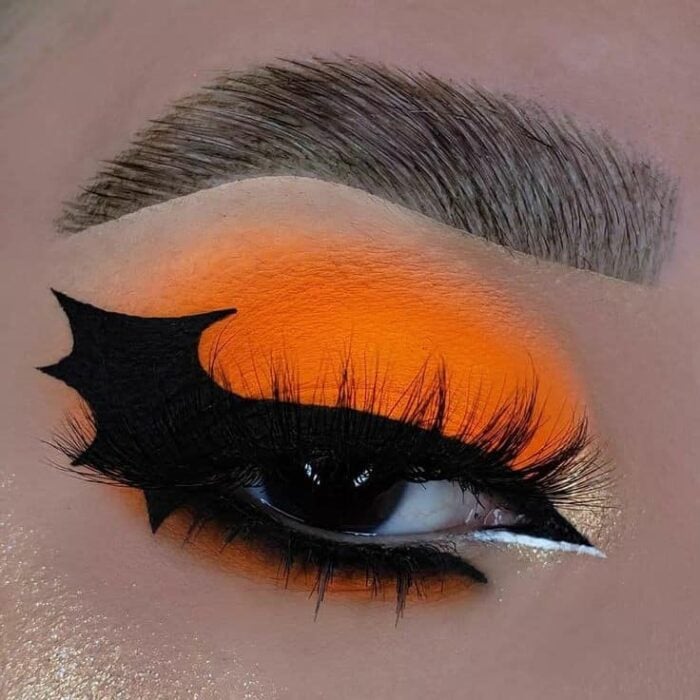 foto deun ojo delineado en color naranja con un ala de murciélago en color negro 