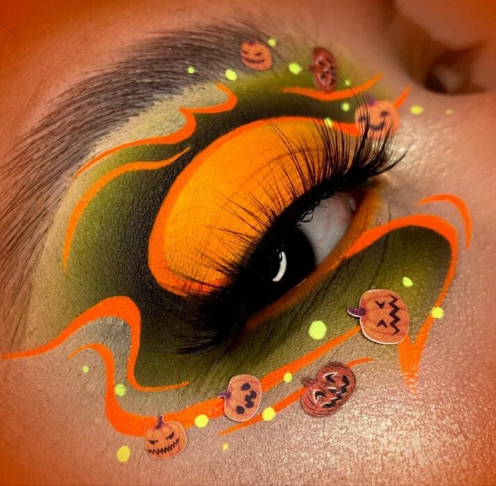 foto de un ojo delineado de colores naranja y verde rodeado de calabazas 