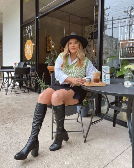 chica sentada afuera de una cafetería, tomando café