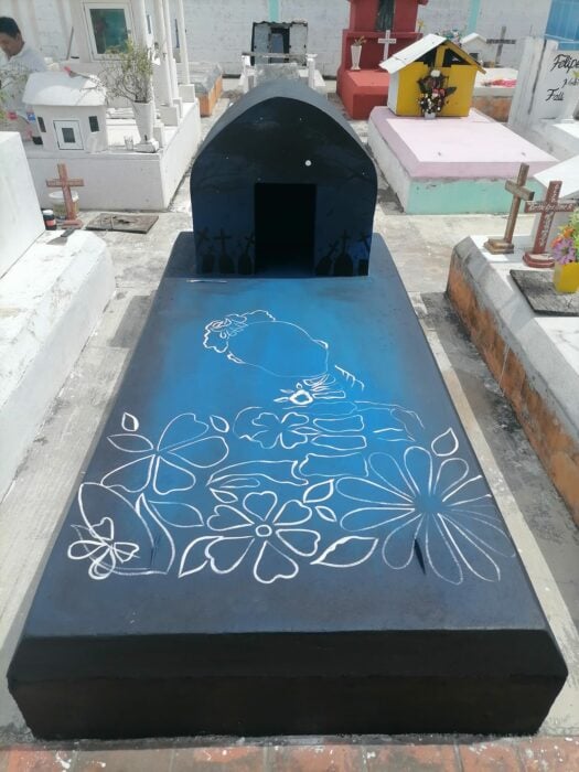 imagen de una tumba pintada de azul con negro y un boceto de dibujo en color blanco 