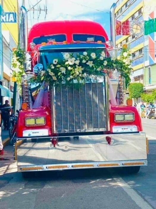 Foto de un trailer color rojo adornado con flores blancas 