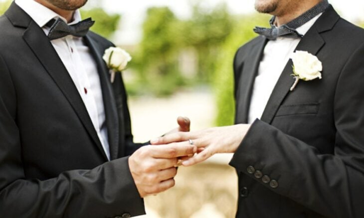 imagen de una pareja de hombres poniéndose el anillo de compromiso