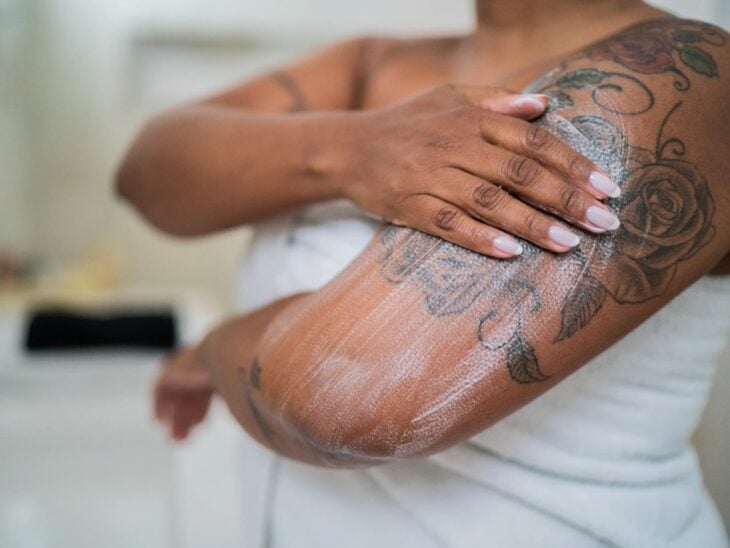 mano de una mujer poniendo crema sobre un tatuaje en su brazo 