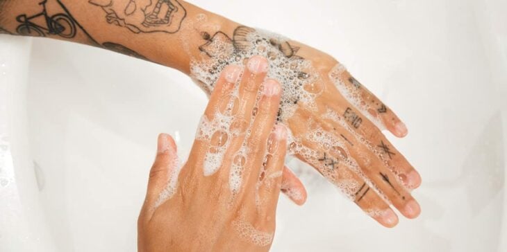 Imagen que muestra unas manos con tatuajes tallándose con jabón