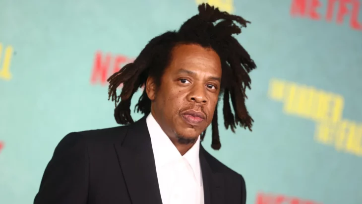 Jay Z peinado con sus inseparables rastas lleva un saco negro y una camisa blanca