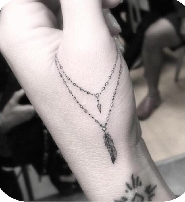 fotografía de la mano de una chica mostrando el tatuaje de una pulsera sobre su dedo pulgar 