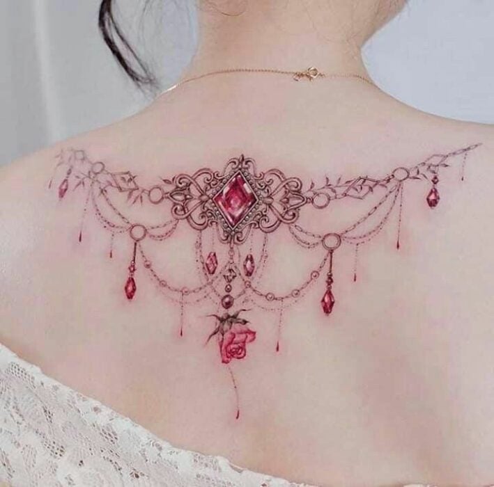 tatuaje de una gargantilla color rosa en la espalda de una chica 