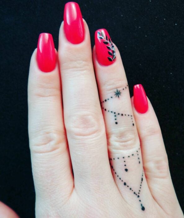imagen de la mano de una mujer mostrando su tatuajes en el dedo anular 