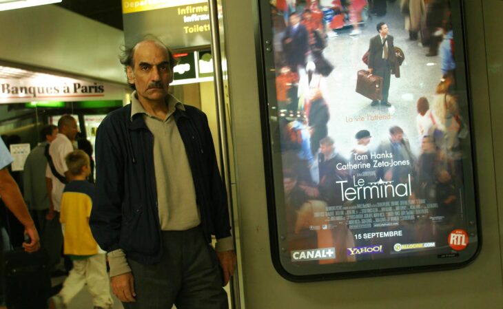 Mehran Karimi Nasseri next to the flyer of the film the terminal 