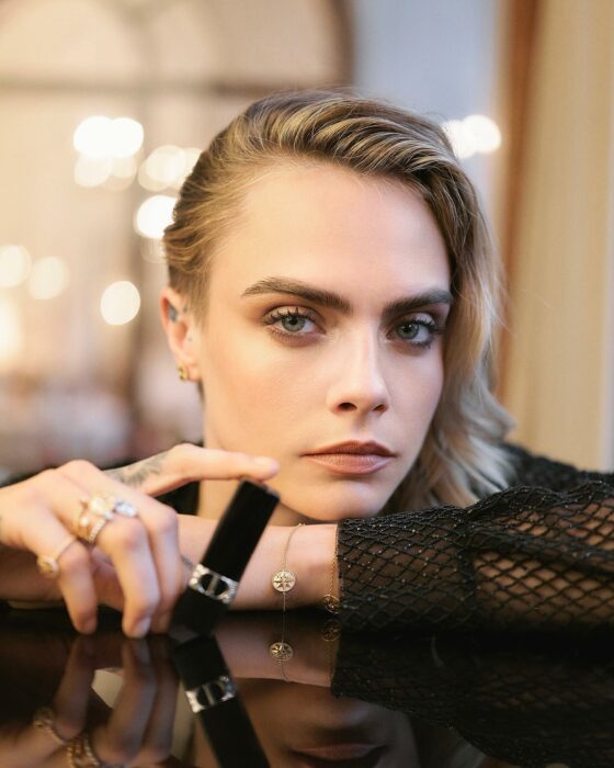 cara delevingne sitting in a black dress