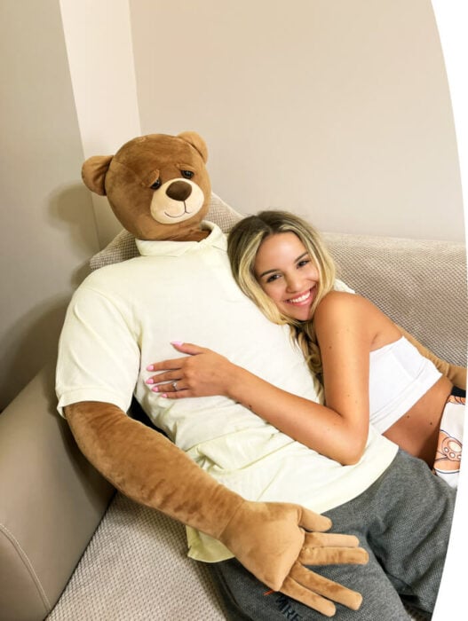 Woman leaning on giant teddy bear for emotional support