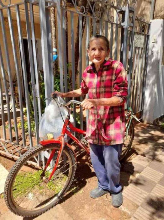 abuelita parada a un lado de una bicicleta roja