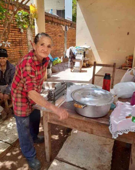 abuelita rodeada de ollas, mesa y todo el material para hacer empanadas 