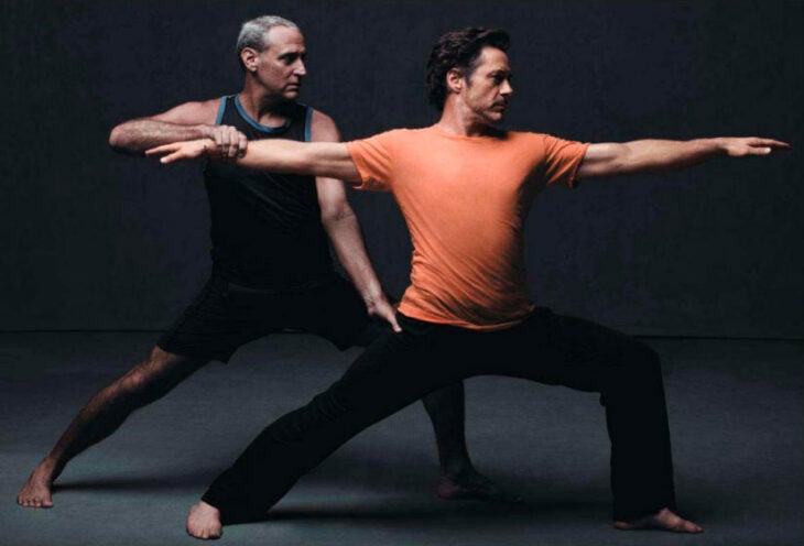 Robert Downey Jr practicando alguna técnica oriental lleva una playera naranja y pants negro su instructor lo va guiando en el movimiento