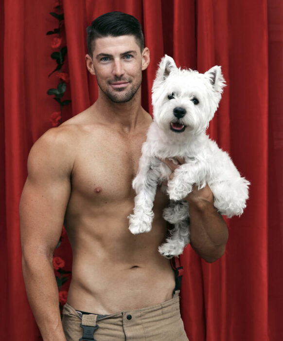 bombero posando para calendario benéfico con un perrito 