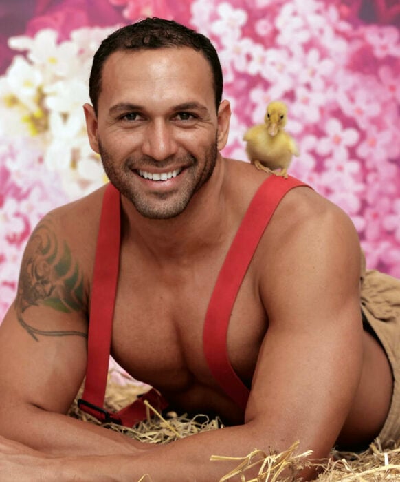 firefighter posing for charity calendar with a duck on his shoulder 