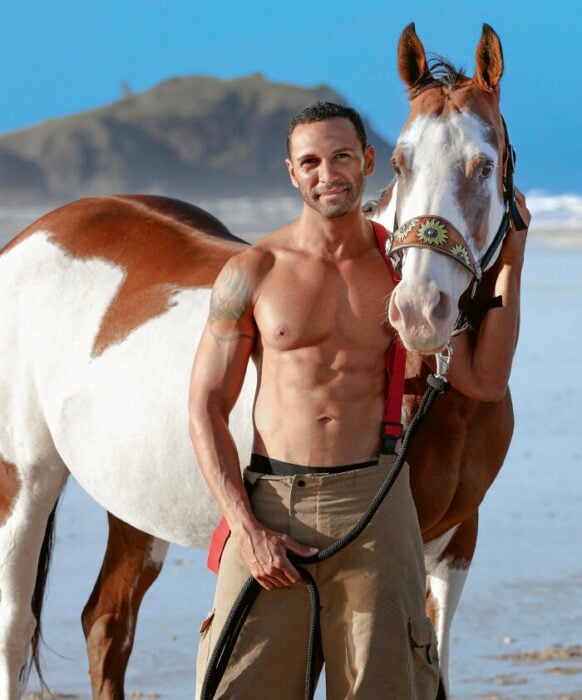bombero posando para calendario benéfico con un caballo en la playa 