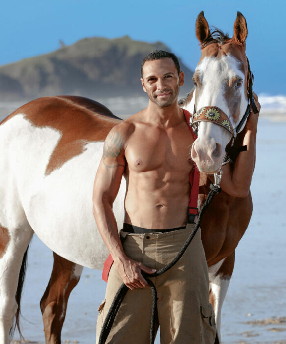 firefighter posing for charity calendar with a horse on the beach 