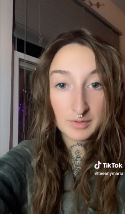 imagen de TikTok de una chica que lleva el cabello largo ondulado suelto tiene un piercing en la nariz y un tatuaje en el cuello