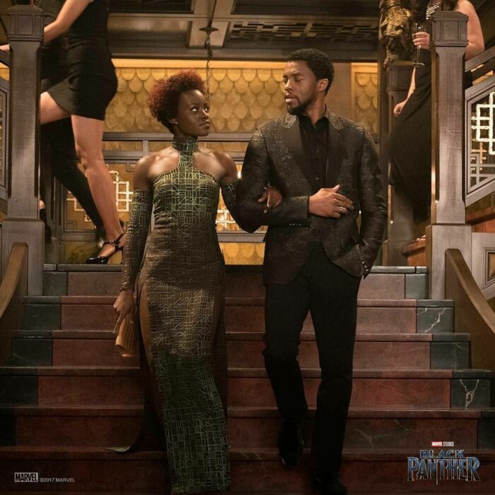 Escena de la película de Black Panther en la que Nakia y el rey T'Challa bajan de unas escaleras tomados del brazo 