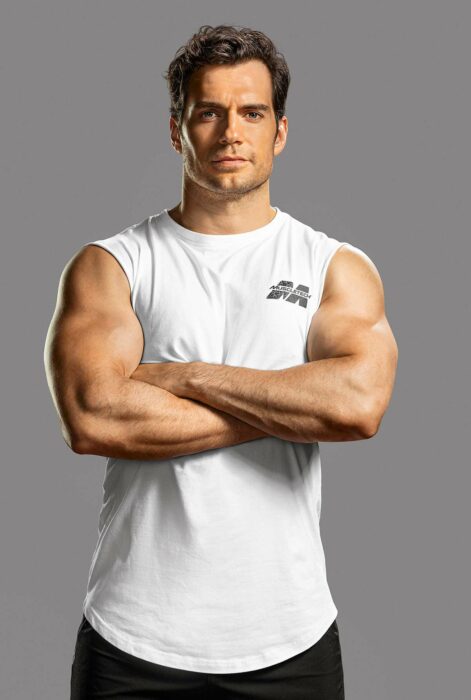 imagen de Henry Cavill vestido con una playera deportiva blanca y un pantalón deportivo negro tiene los brazos cruzados haciendo resaltar los músculos de sus tríceps