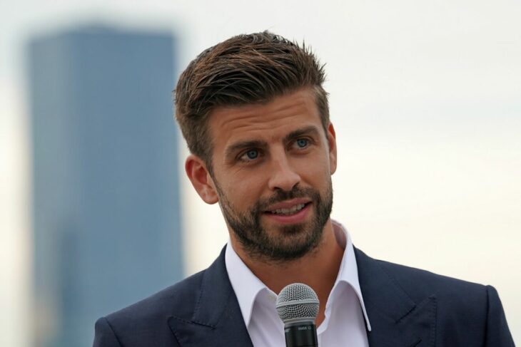 handsome man speaking into a microphone, wearing a navy blue suit, white shirt without a tie