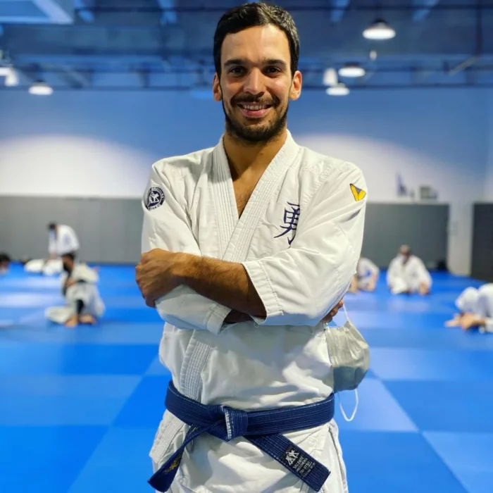 un profesor de artes marciales en su gimnasio posando con su traje blanco y cinta negra