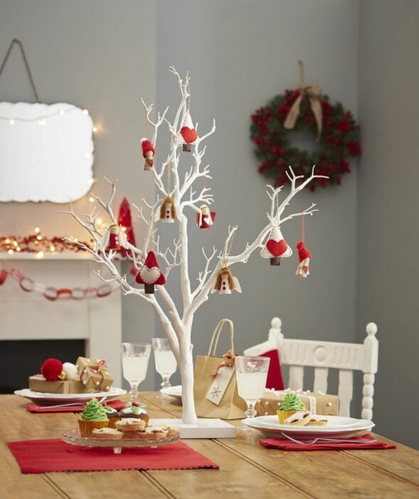 comedor de una casa con decoración navideña y un árbol navideño con ramas secas como centro de mesa 
