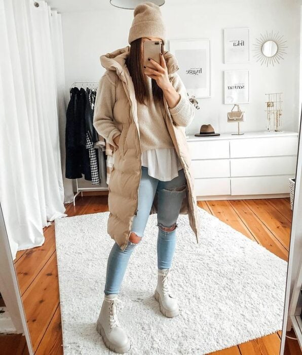 chica tomándose una foto en el espejo usando un chaleco oversized a juego con unas botas y un gorro de invierno