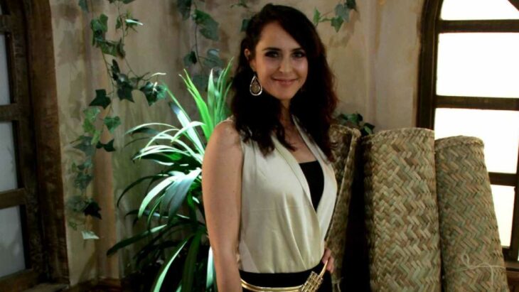 girl posing in a white sleeveless dress, in the background there are some green natural plants