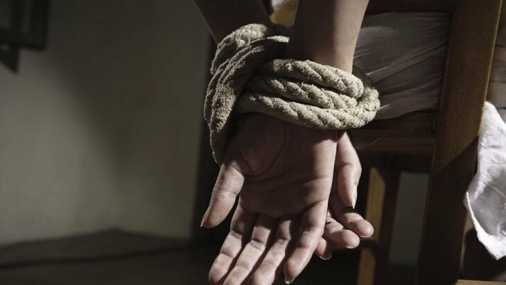 hands tied with a rope you can see a person sitting on a chair with his arms behind his back