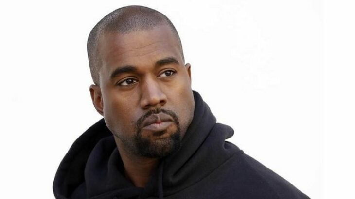 imagen de Kanye West lleva una sudadera negra con capucha y esta mirando en otra dirección